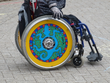 Photo of a child in a wheelchair with colorfull custom wheel covers
